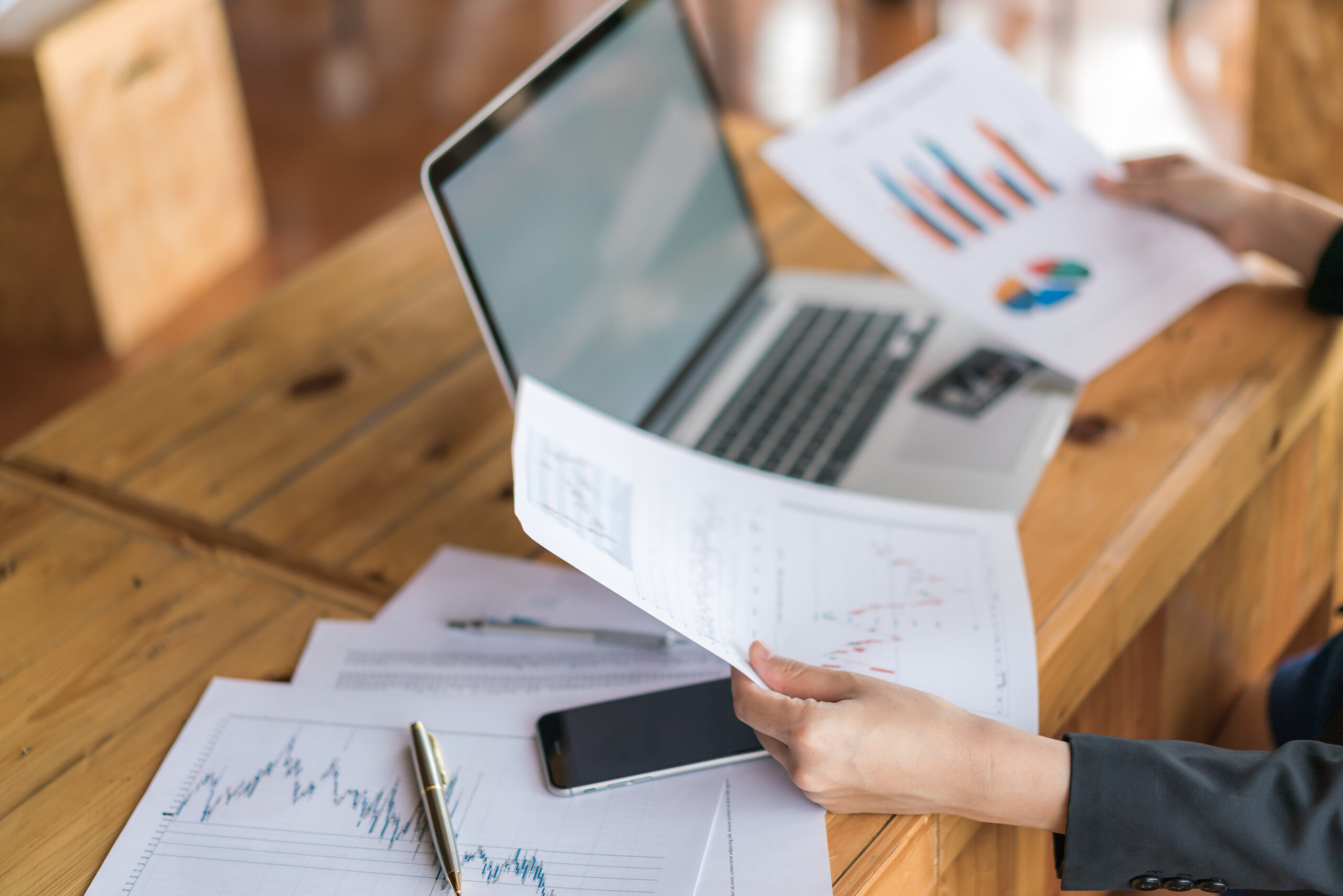 Business woman hand with Financial charts and laptop on the table